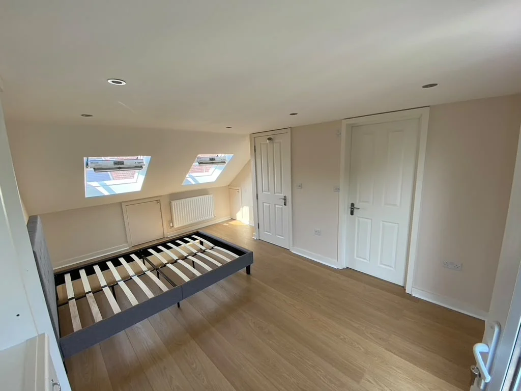 Finished loft bedroom with white walls and fitted wardrobes